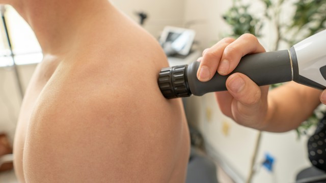Illustrative photo of a handheld massage device applied to a shoulder